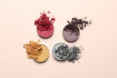 Different crushed eye shadows on beige background, flat lay