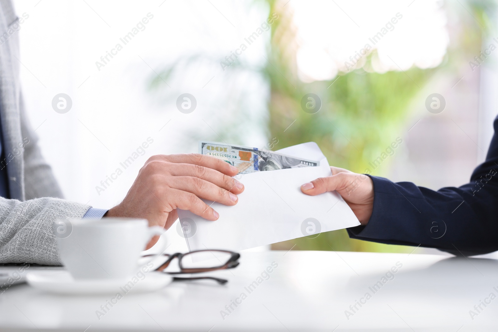 Photo of Woman giving bribe to man at table indoors, closeup