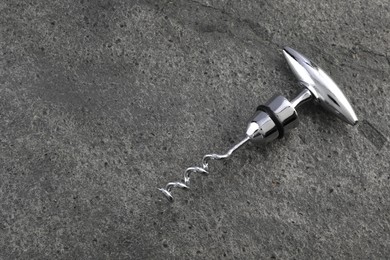 Photo of One metal corkscrew on grey textured table, top view. Space for text