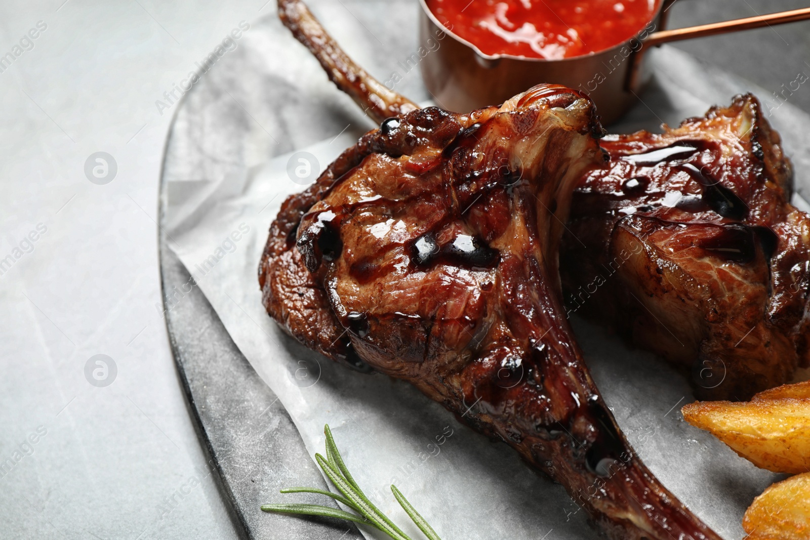 Photo of Delicious grilled ribs served on light table, closeup