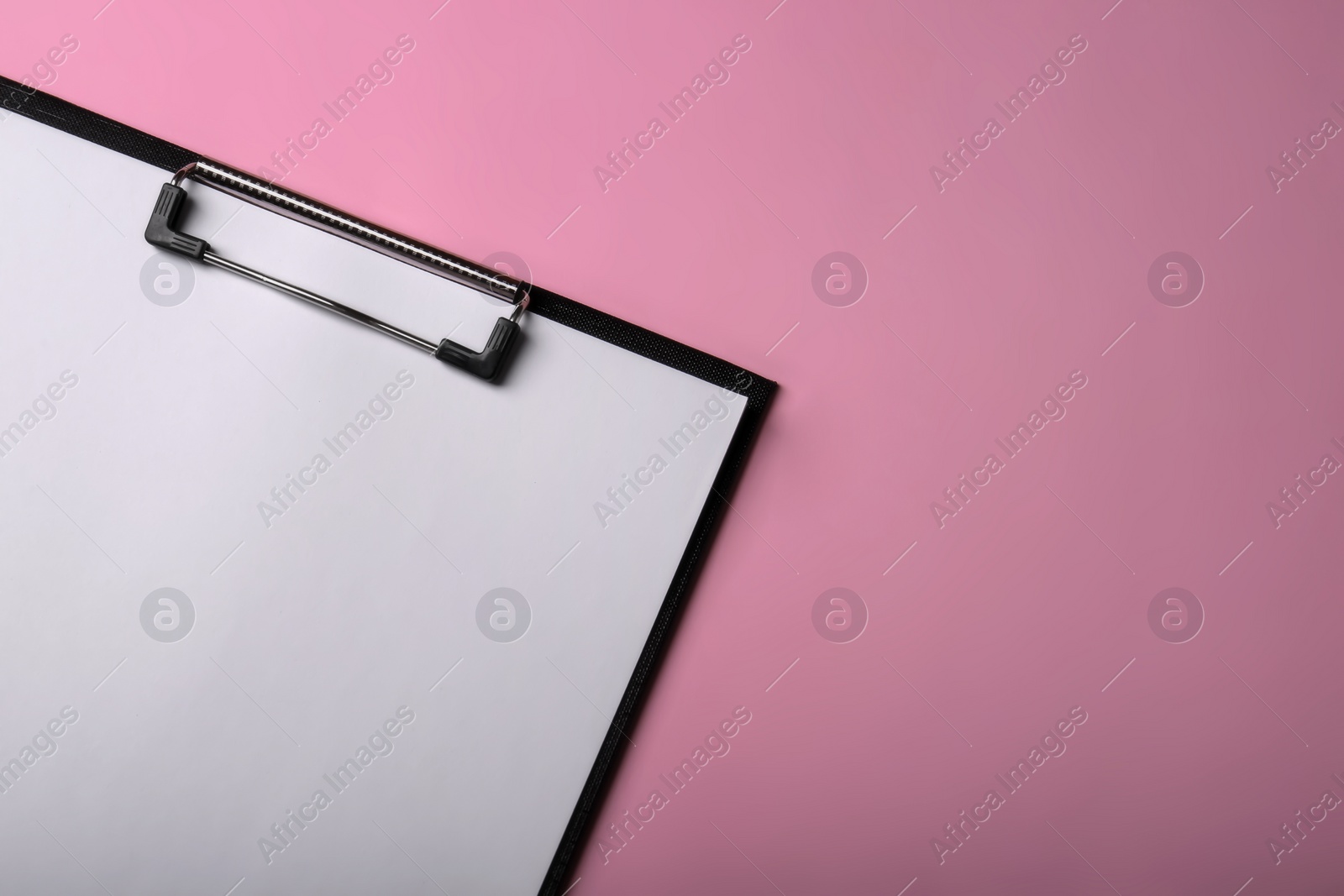 Photo of Black clipboard with sheet of blank paper on pink background, top view. Space for text