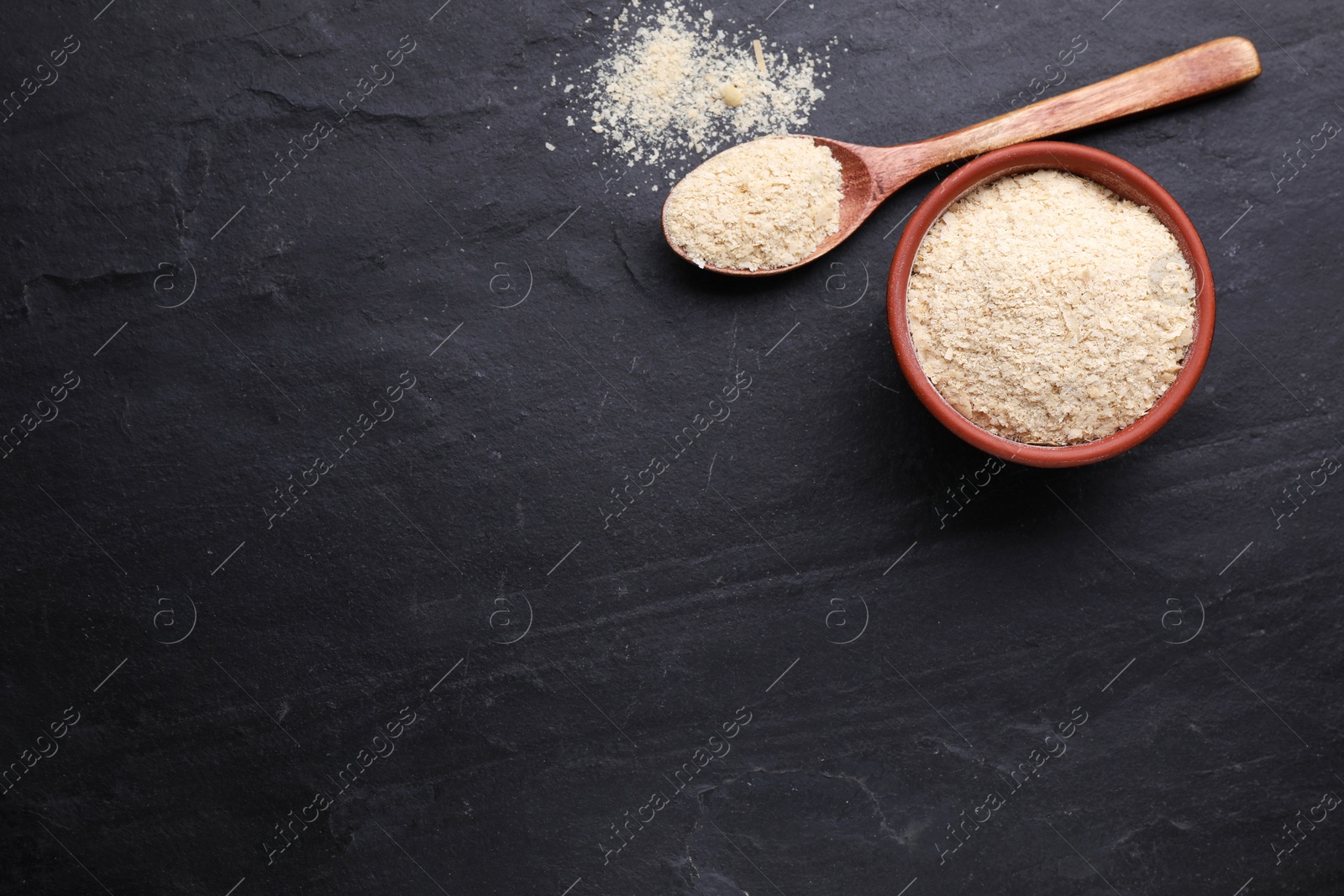 Photo of Brewer's yeast flakes on black table, flat lay. Space for text