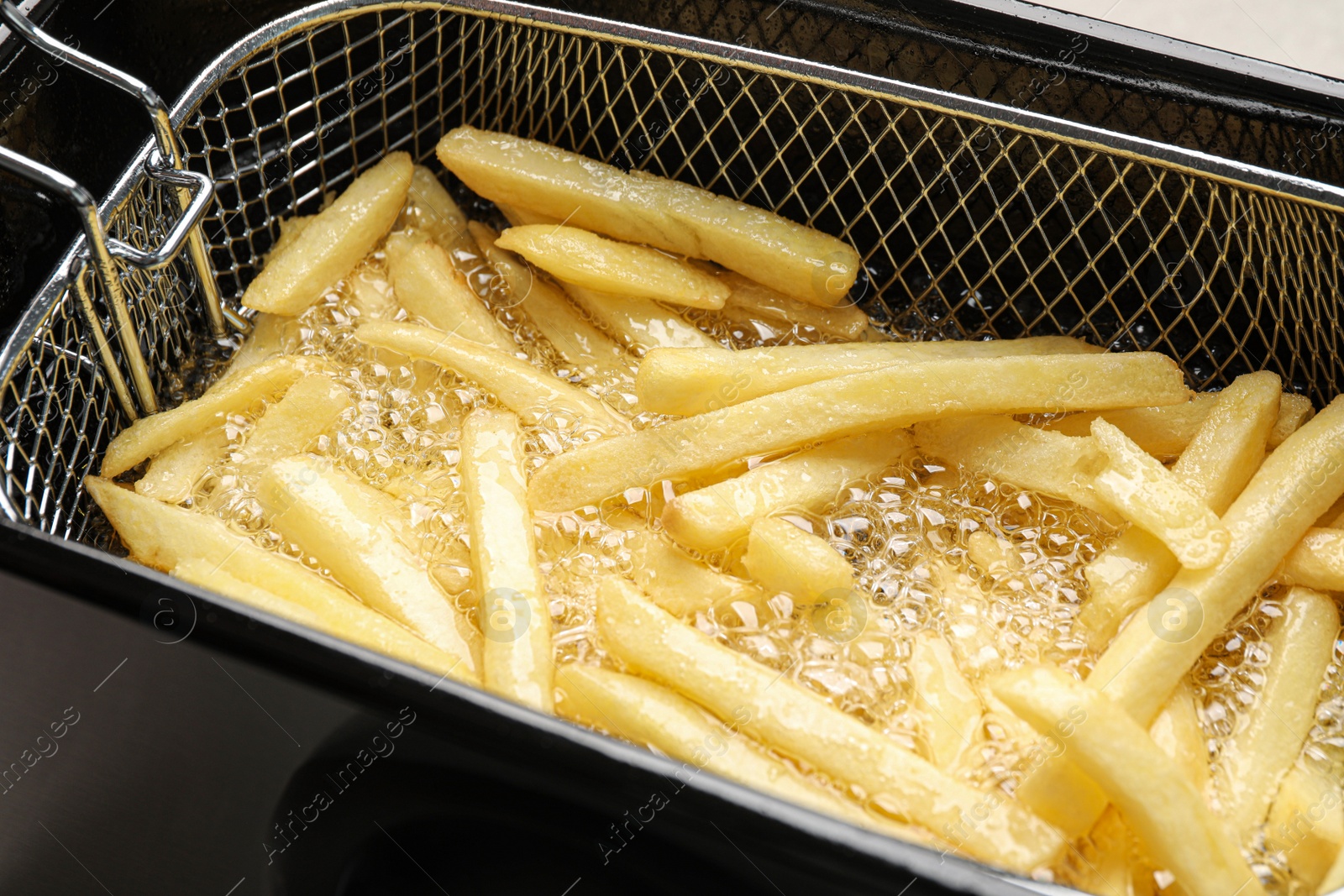 Photo of Cooking delicious french fries in hot oil, closeup