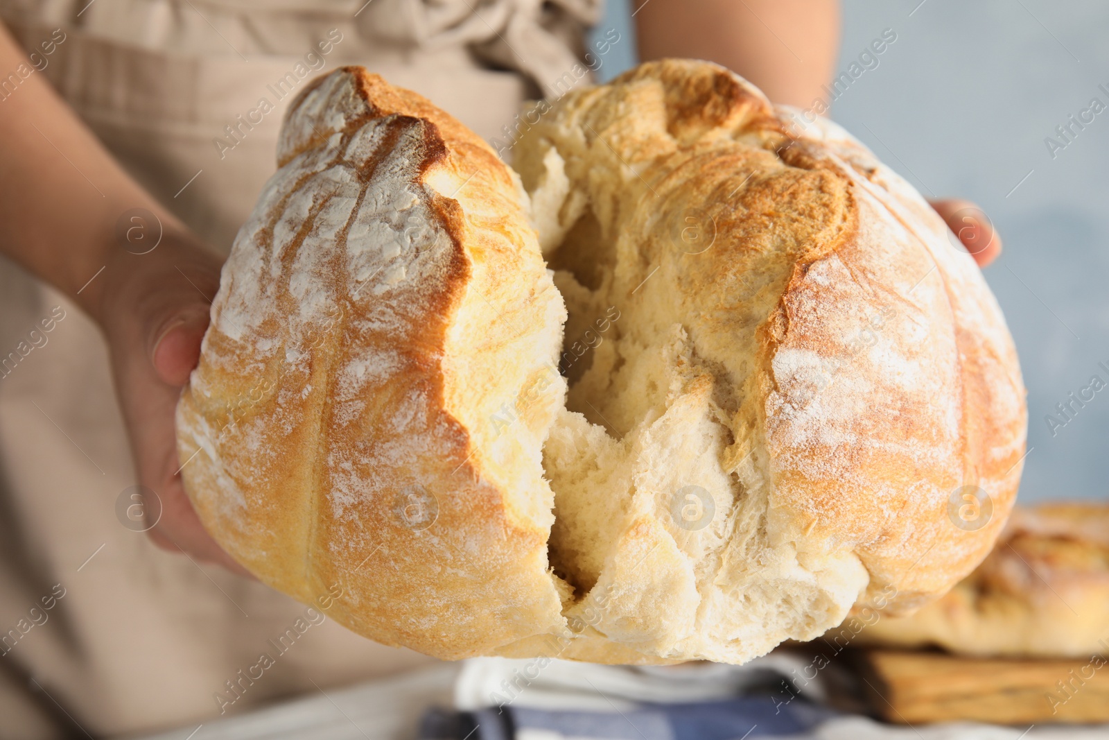 Photo of Man holding whole wheat bread over table, closeup