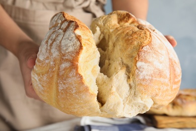 Photo of Man holding whole wheat bread over table, closeup