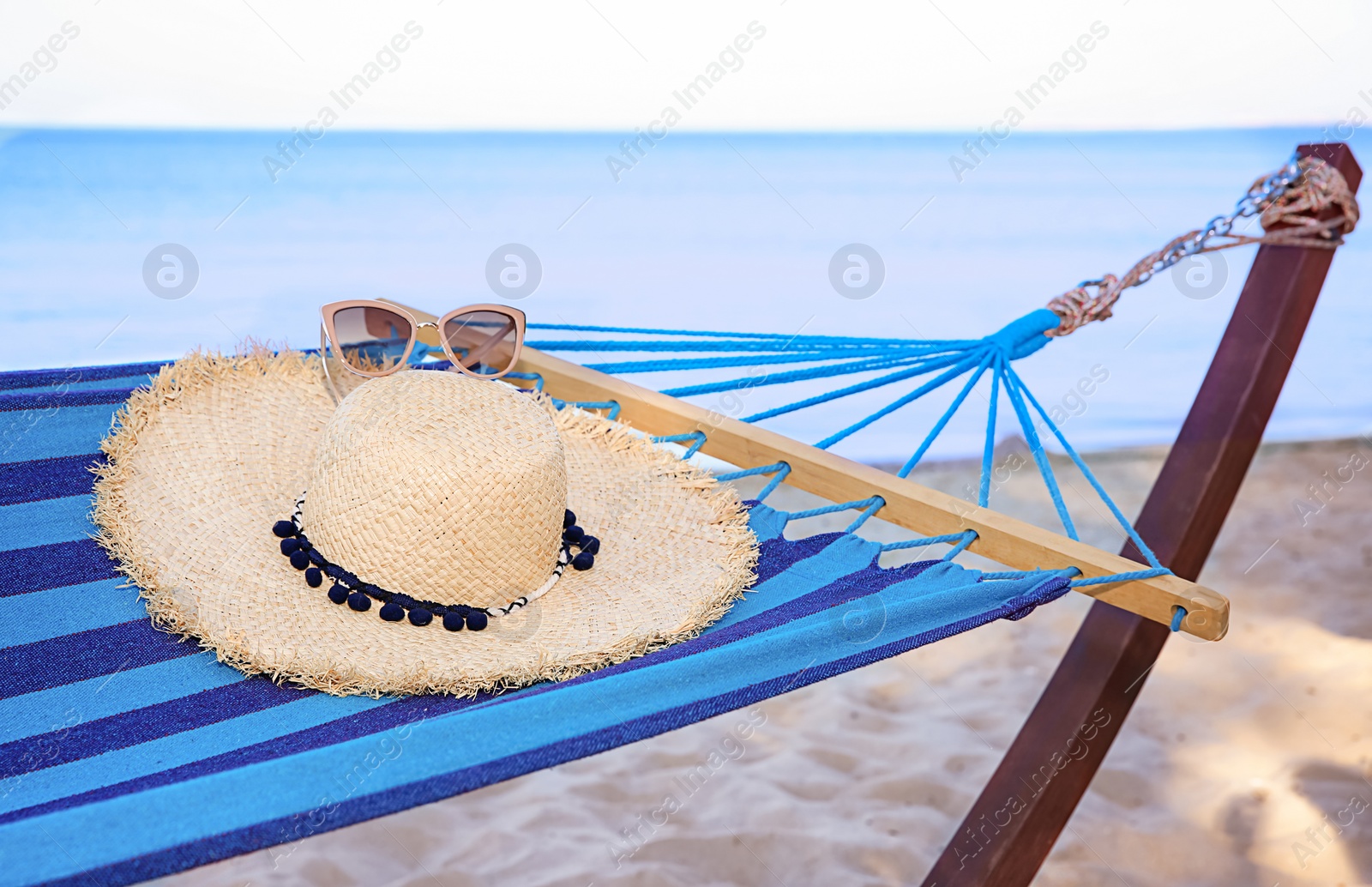 Photo of Comfortable hammock with straw hat and sunglasses at seaside