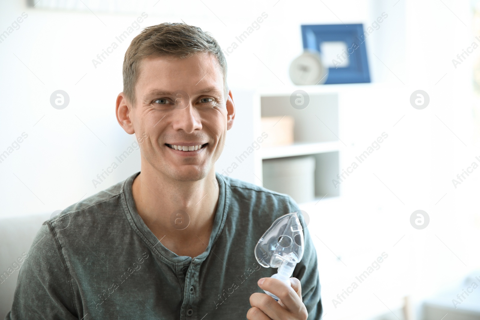 Photo of Young man using asthma machine indoors. Space for text