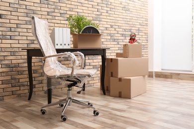 Photo of Furniture and moving boxes in empty office