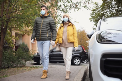 Couple in medical face masks and gloves walking outdoors. Personal protection during COVID-19 pandemic