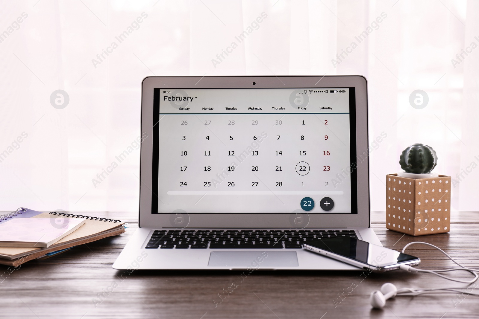 Photo of Laptop with calendar on wooden table at workplace