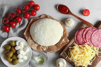 Photo of Pizza dough and products on gray textured table, flat lay