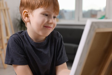 Photo of Little boy painting on canvas in studio