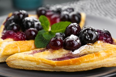 Fresh tasty puff pastry with sugar powder, jam, sweet berries and mint, closeup