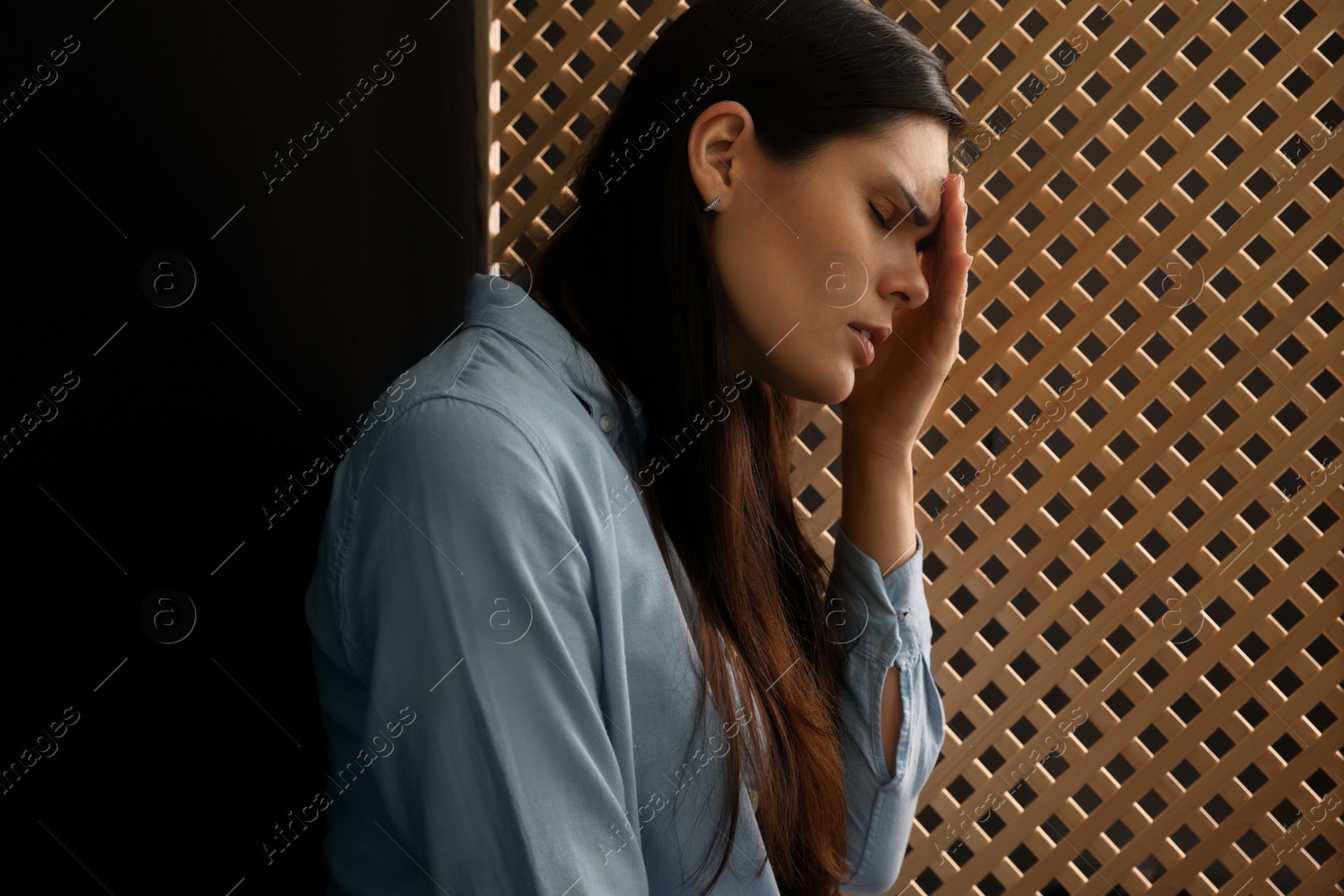 Photo of Upset woman listening to priest during confession in booth