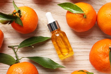 Photo of Bottle of tangerine essential oil and fresh fruits on white wooden table, flat lay