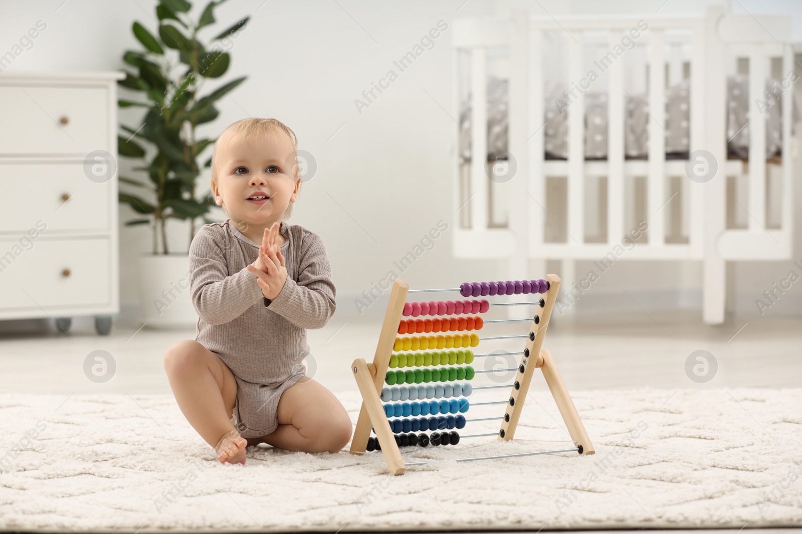 Photo of Children toys. Cute little boy and wooden abacus on rug at home