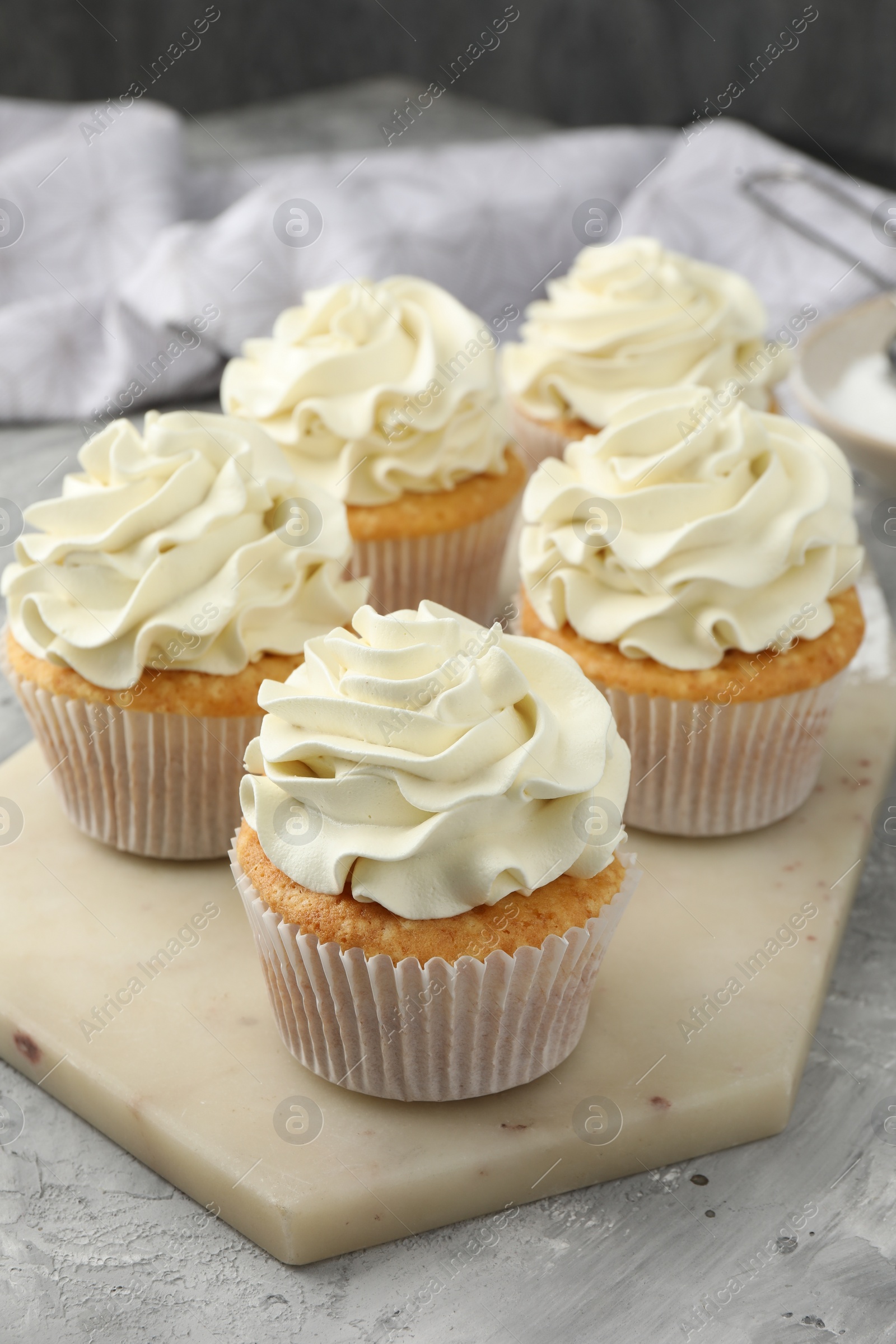 Photo of Tasty cupcakes with vanilla cream on grey table, closeup