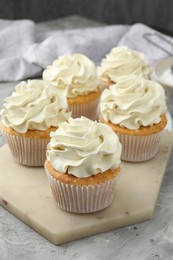 Tasty cupcakes with vanilla cream on grey table, closeup