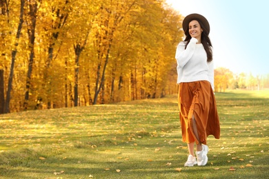 Beautiful happy woman wearing hat walking in autumn park