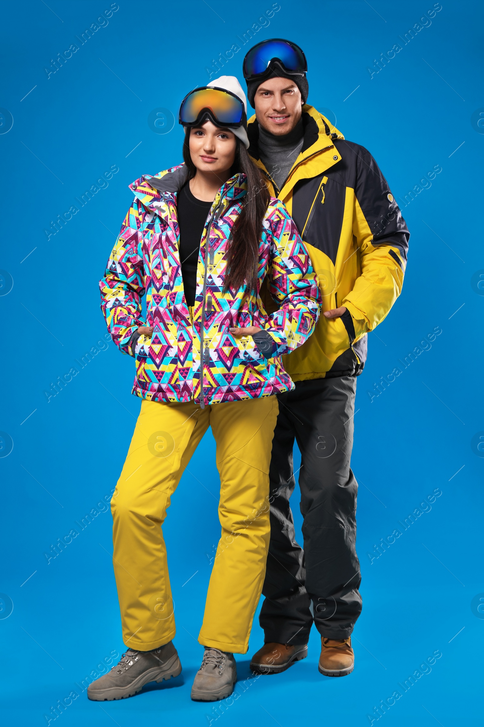 Photo of Couple wearing stylish winter sport clothes on light blue background