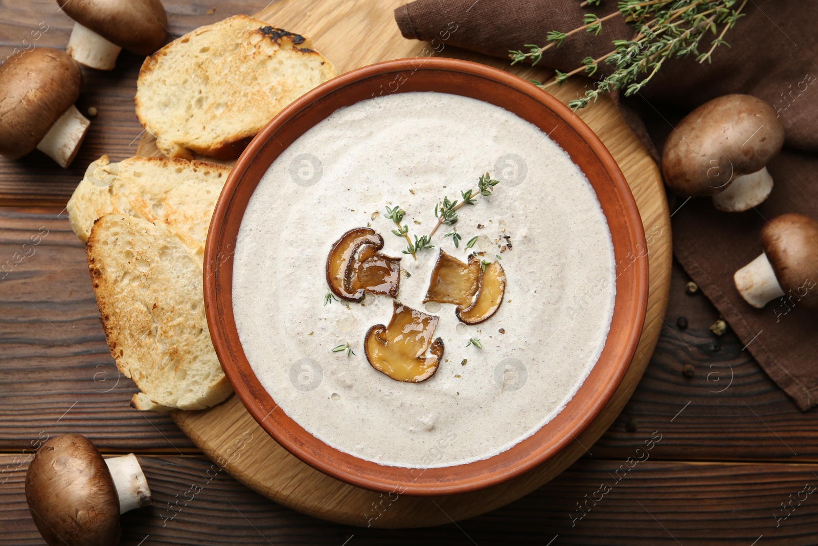 Photo of Fresh homemade mushroom soup in ceramic bowl on wooden table, flat lay