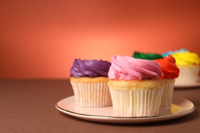 Delicious cupcakes with bright cream on color background, space for text