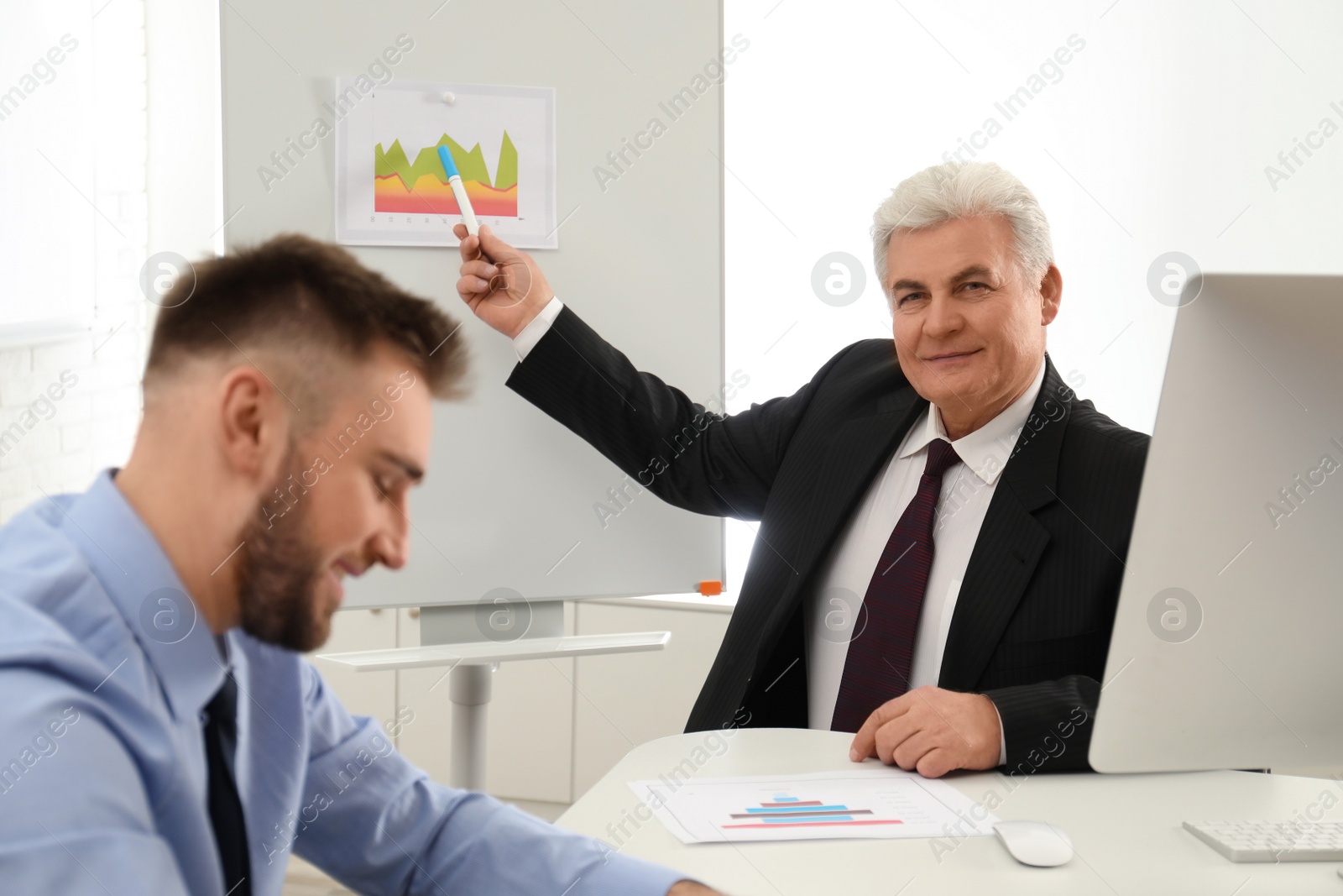 Photo of Senior business trainer working with people in office