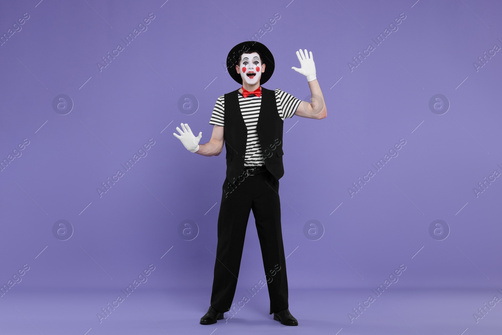 Photo of Mime artist making excited face on purple background