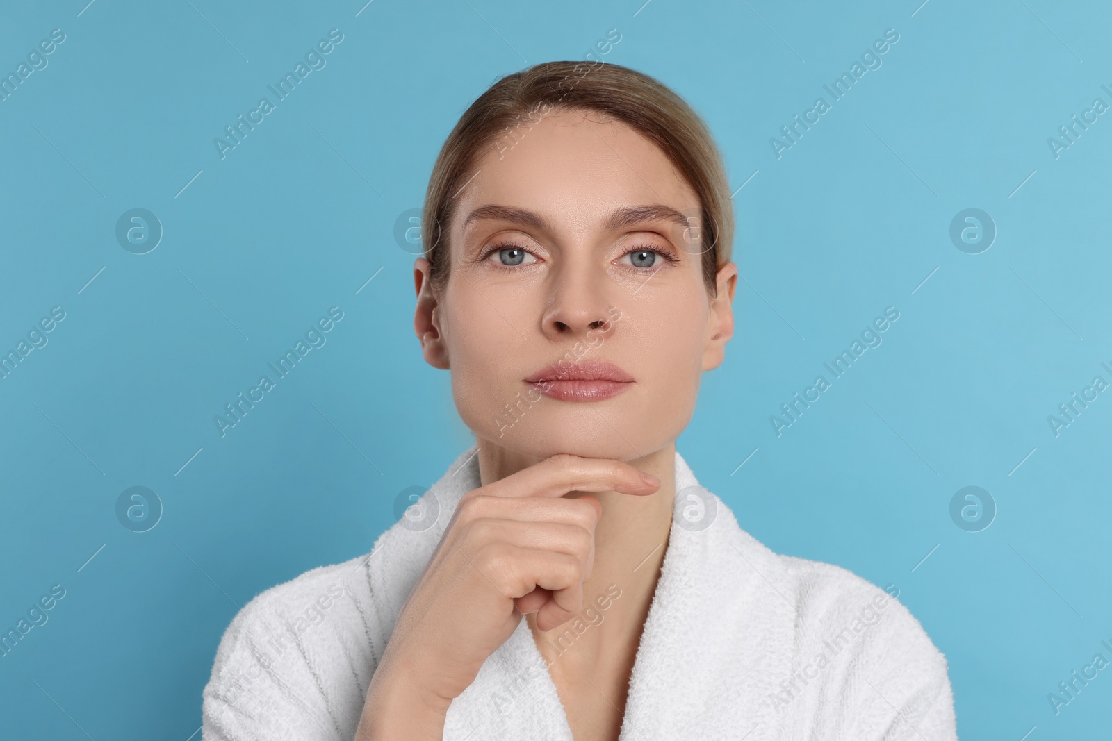 Photo of Woman massaging her face on turquoise background