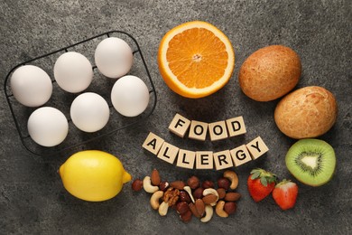 Image of Food allergy. Different fresh products and wooden cubes on grey table, flat lay