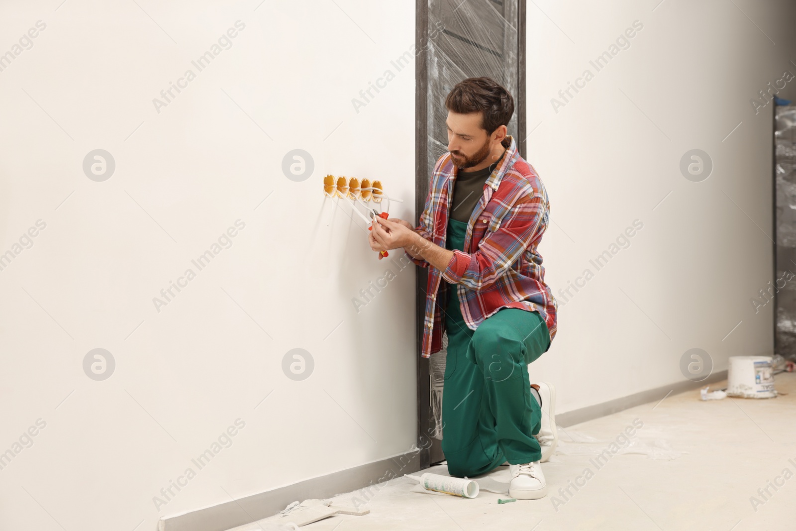 Photo of Professional electrician with pliers fixing wires indoors