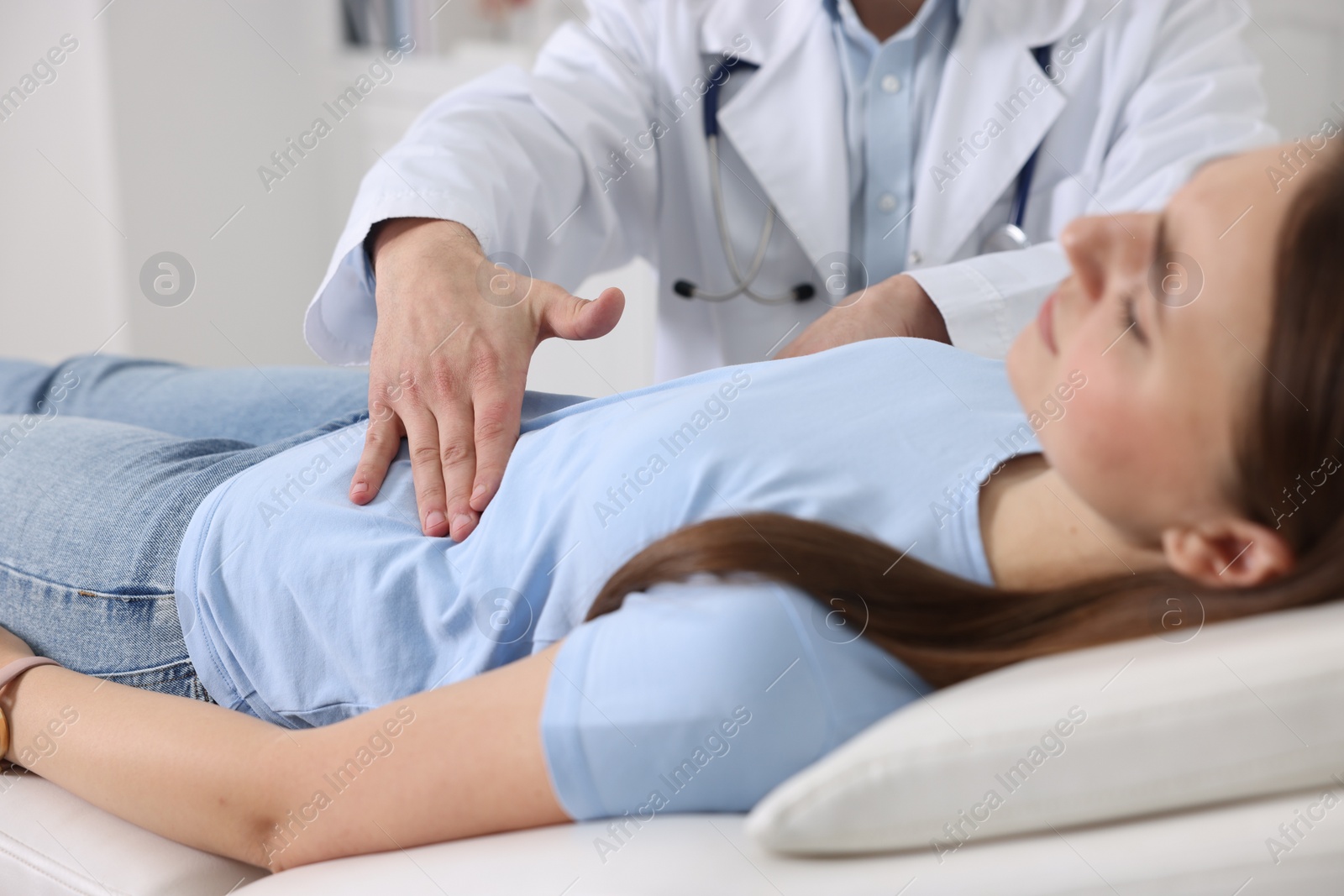 Photo of Gastroenterologist examining patient with stomach pain on couch in clinic, closeup