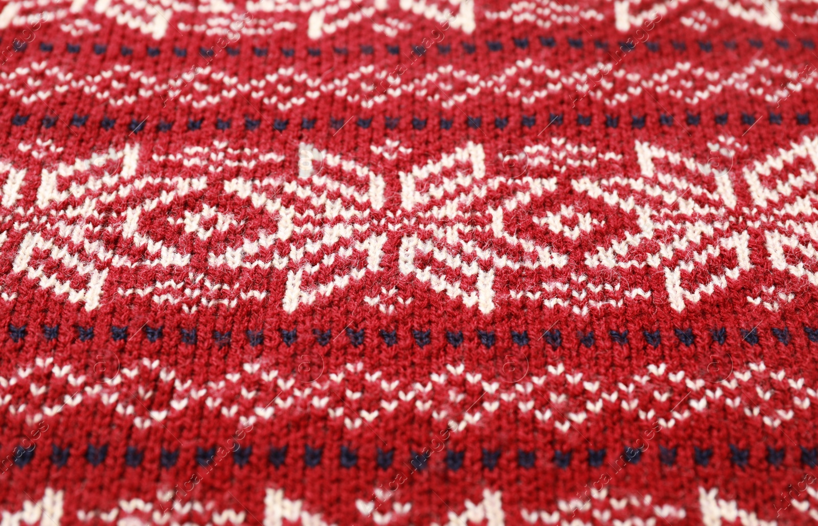 Photo of Warm Christmas sweater with snowflakes as background, closeup