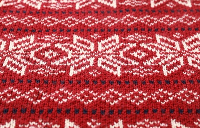 Photo of Warm Christmas sweater with snowflakes as background, closeup