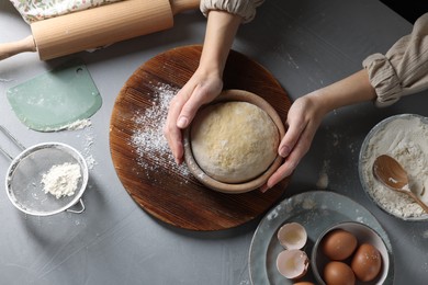 Woman making dough at grey table, top view