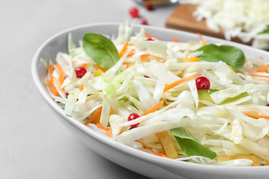Photo of Fresh cabbage salad served on light grey table, closeup
