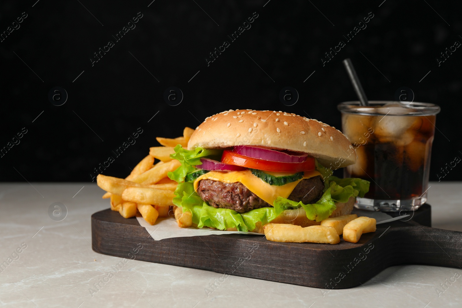 Photo of Delicious burger, soda drink and french fries served on grey marble table