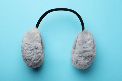 Photo of Stylish warm earmuffs on light blue background, top view