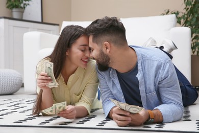 Photo of Happy couple with money on floor at home