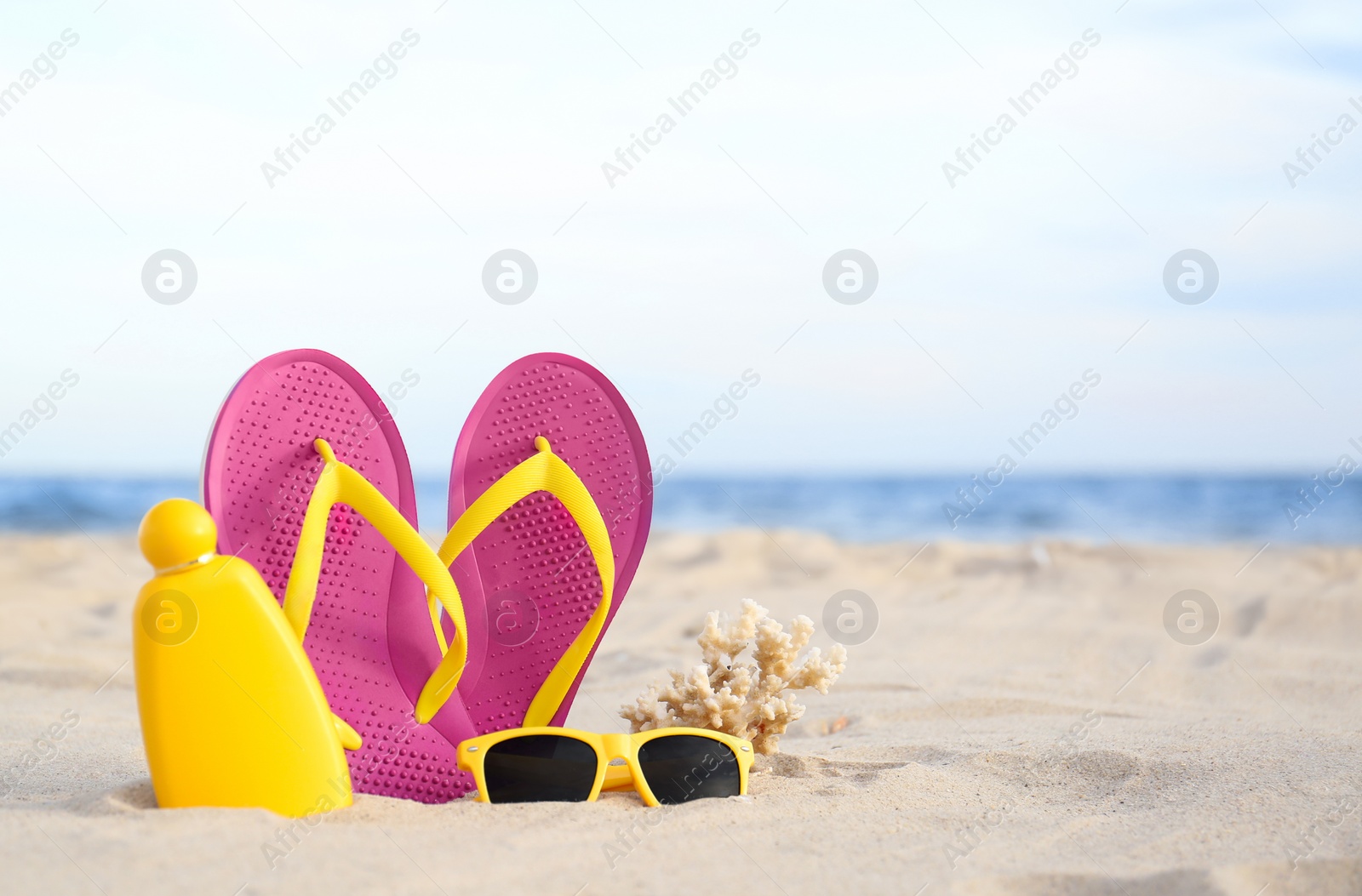 Photo of Different stylish beach objects on sand near sea. Space for text