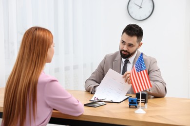 Immigration to United States of America. Embassy worker approving visa application form to woman in office