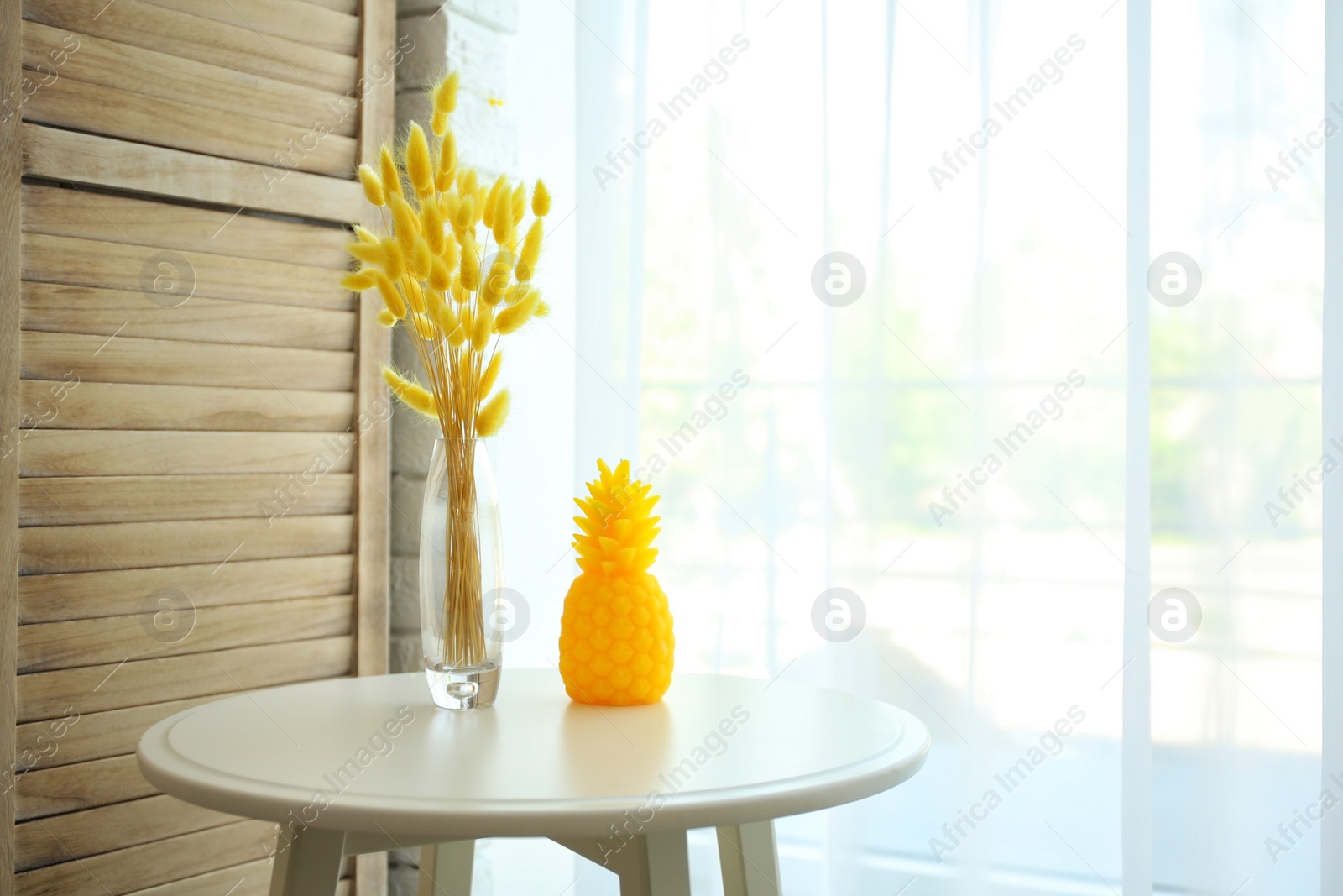 Photo of Stylish pineapple candle on table indoors. Home decorating idea