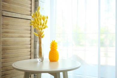 Photo of Stylish pineapple candle on table indoors. Home decorating idea