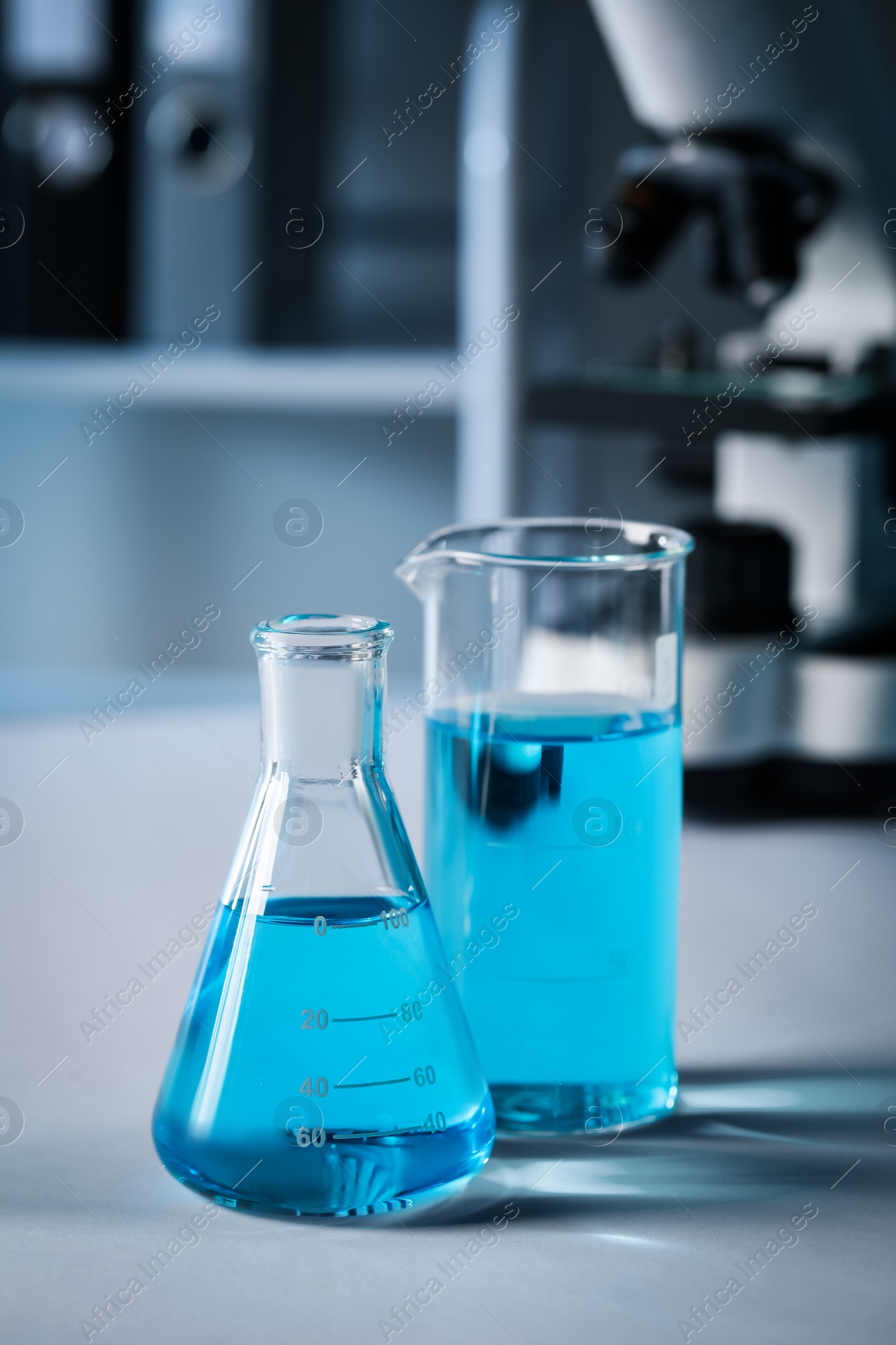 Photo of Different laboratory glassware with light blue liquid on table