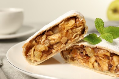 Photo of Delicious strudel with apples, nuts and raisins on plate, closeup