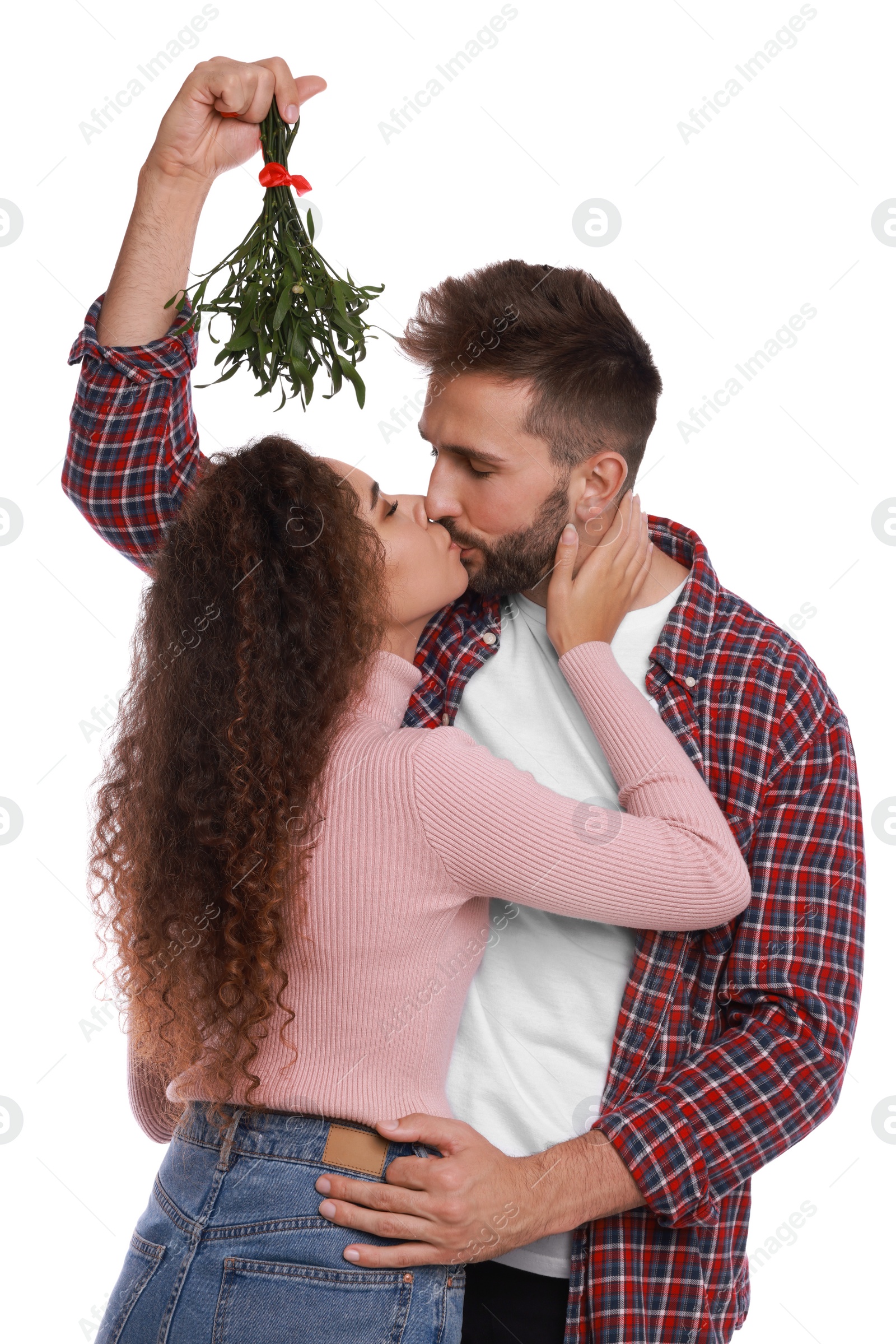 Photo of Happy couple kissing under mistletoe bunch on white background