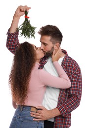 Photo of Happy couple kissing under mistletoe bunch on white background