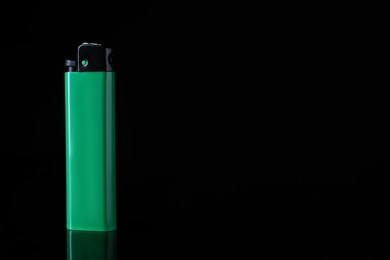 Photo of Green plastic cigarette lighter on black background, space for text