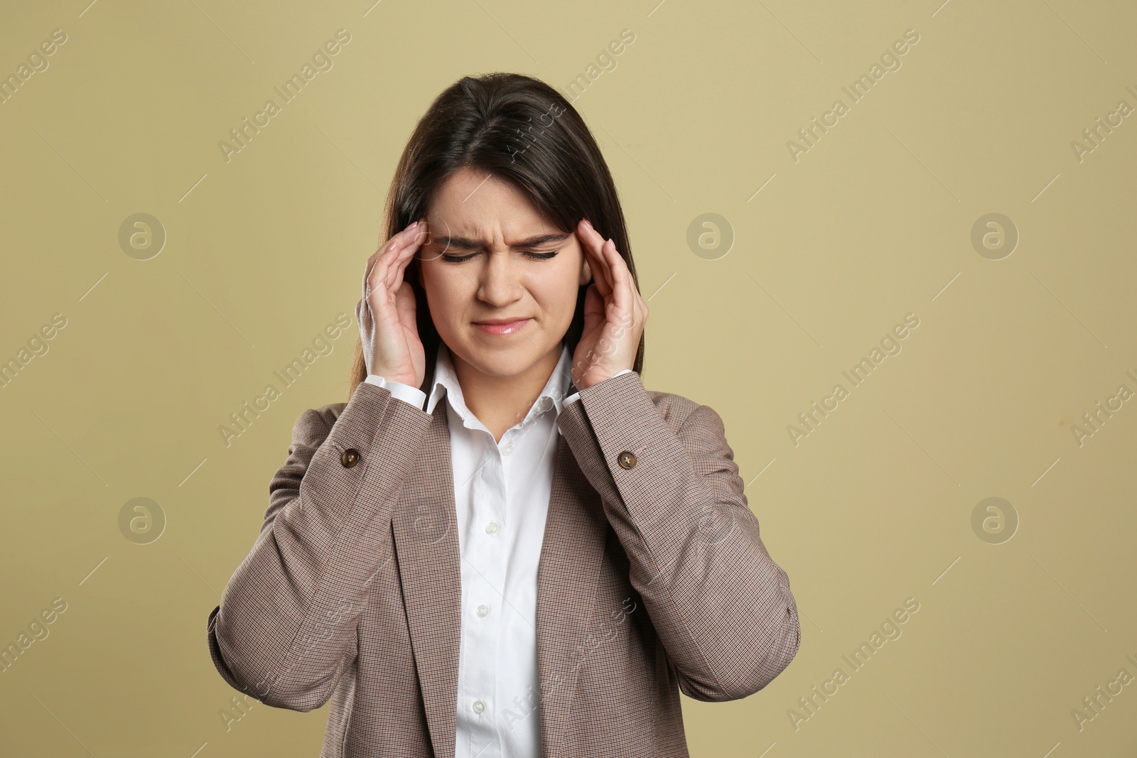 Photo of Young woman suffering from migraine on beige background