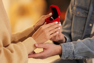 Photo of Man with engagement ring making proposal to his girlfriend against blurred background, closeup